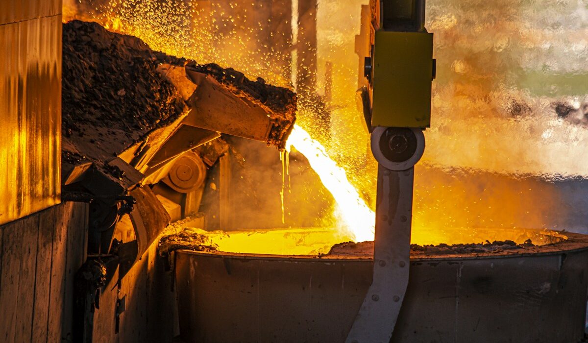 Molten metal pouring into an industrial ladle at a smelter