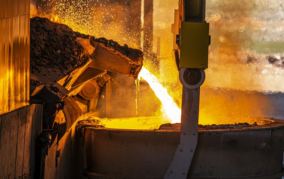 Molten metal pouring into an industrial ladle at a smelter