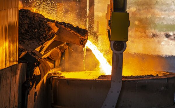 Molten metal pouring into an industrial ladle at a smelter