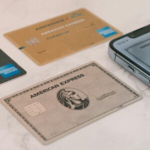 American Express credit cards beside a smartphone illustrating the American Express AML penalty