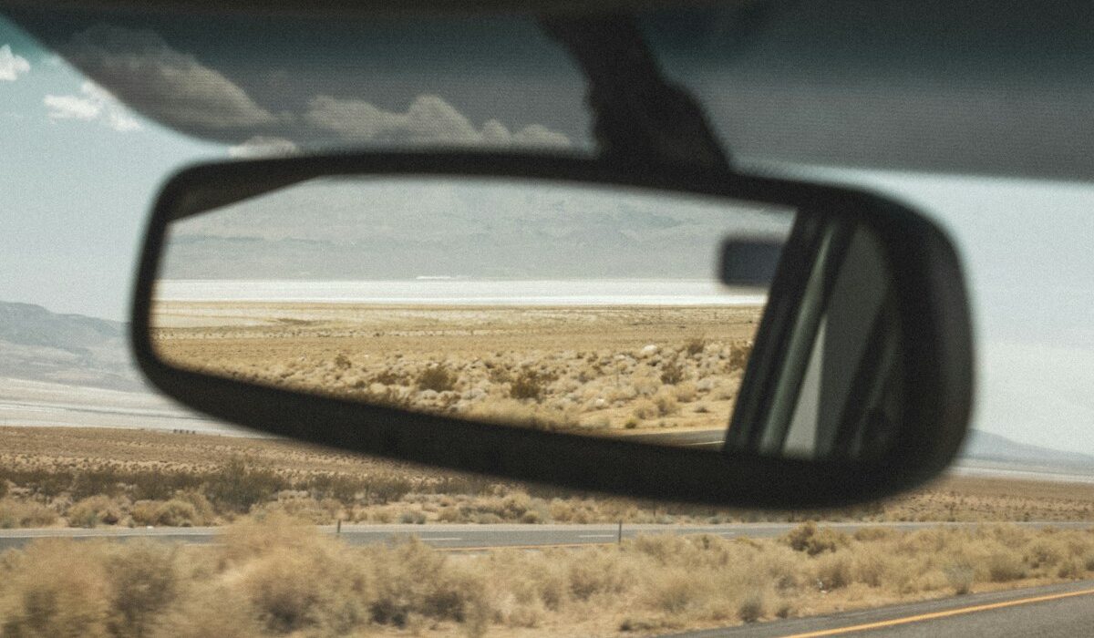Rearview mirror inside a car reflecting a desert highway landscape