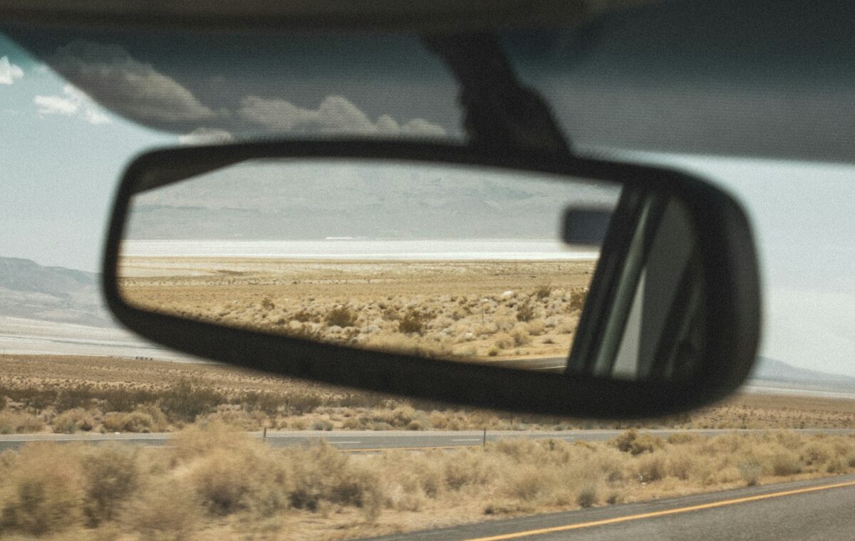 Rearview mirror inside a car reflecting a desert highway landscape