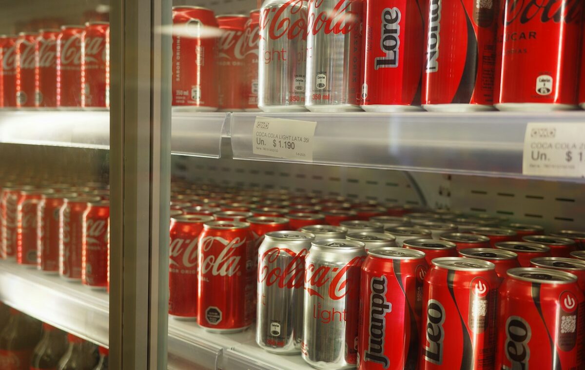 Rows of Coca-Cola cans displayed in a refrigerated retail case