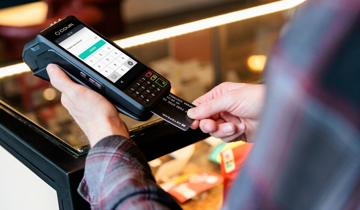 Contactless payment card held beside a digital payment terminal