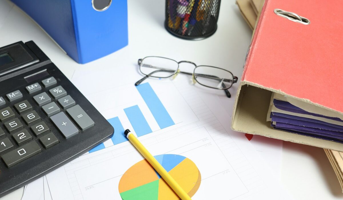Calculator, financial charts and document folders illustrating debt-to-equity analysis. Photo by Cht Gsml on Unsplash.