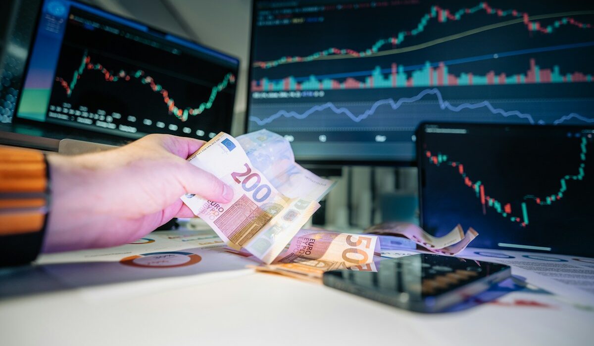 Euro banknote beside financial market screens, illustrating Europe’s T+1 securities settlement shift