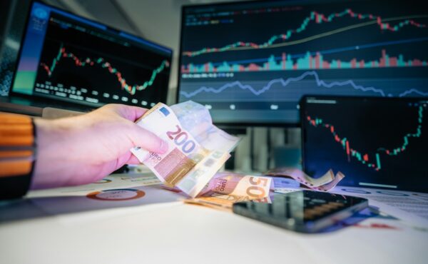 Euro banknote beside financial market screens, illustrating Europe’s T+1 securities settlement shift
