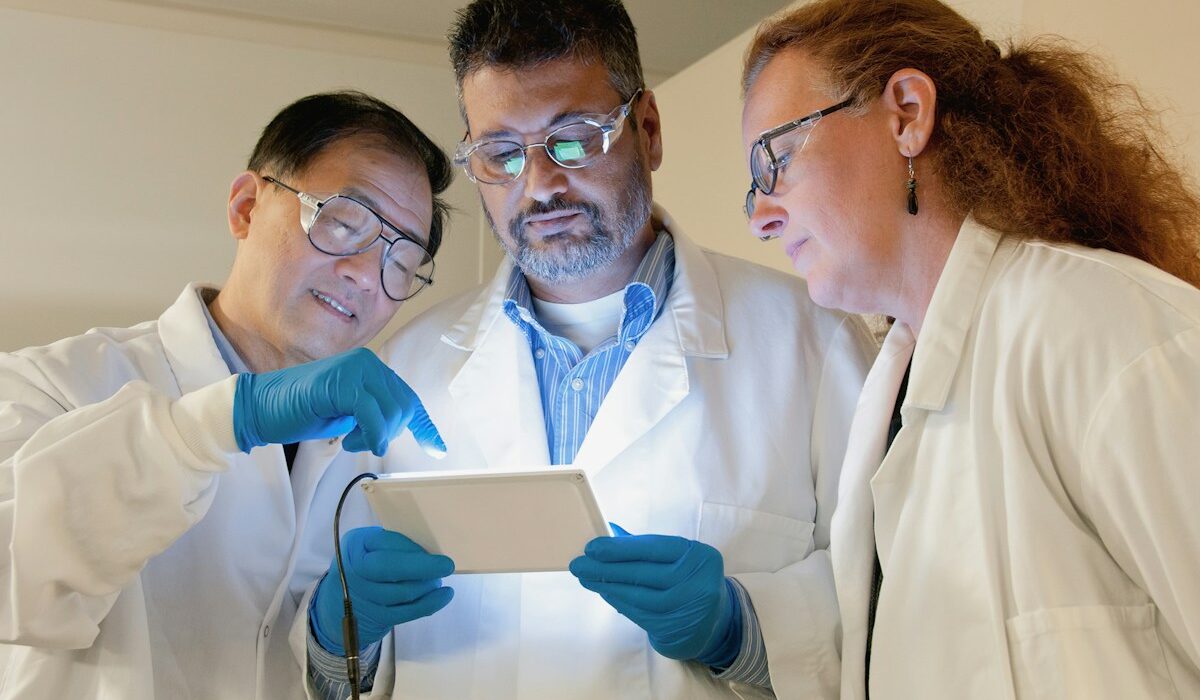 Three biotechnology scientists reviewing cancer research data in a laboratory