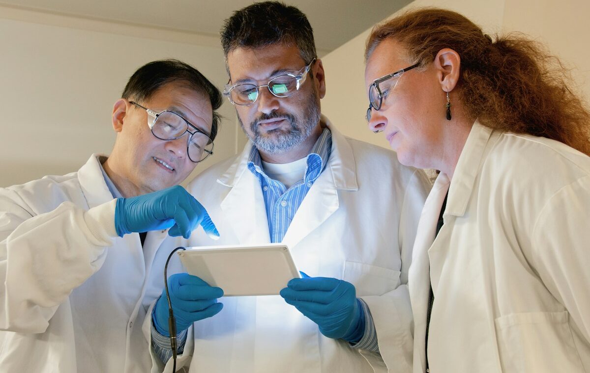 Three biotechnology scientists reviewing cancer research data in a laboratory