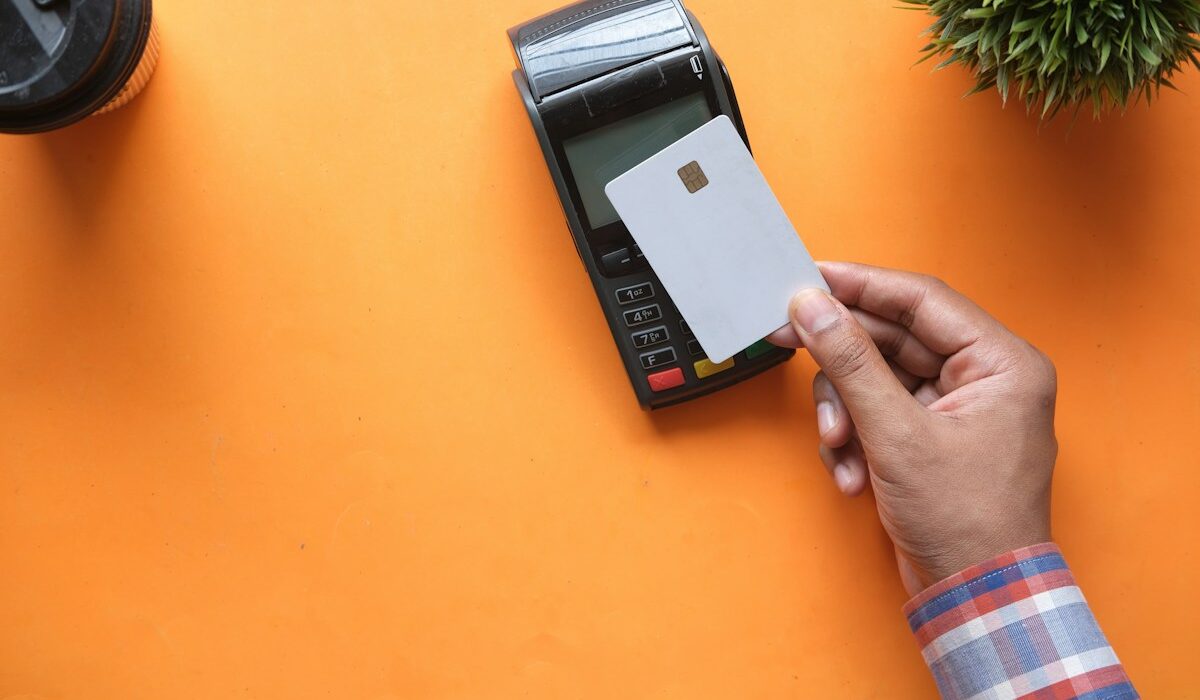 Payment card held near a terminal representing Mastercard bank payout infrastructure