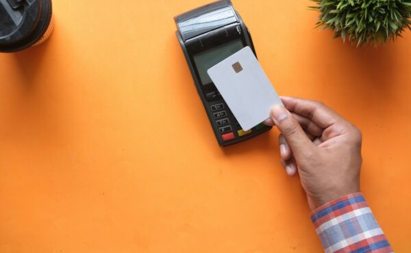 Payment card held near a terminal representing Mastercard bank payout infrastructure