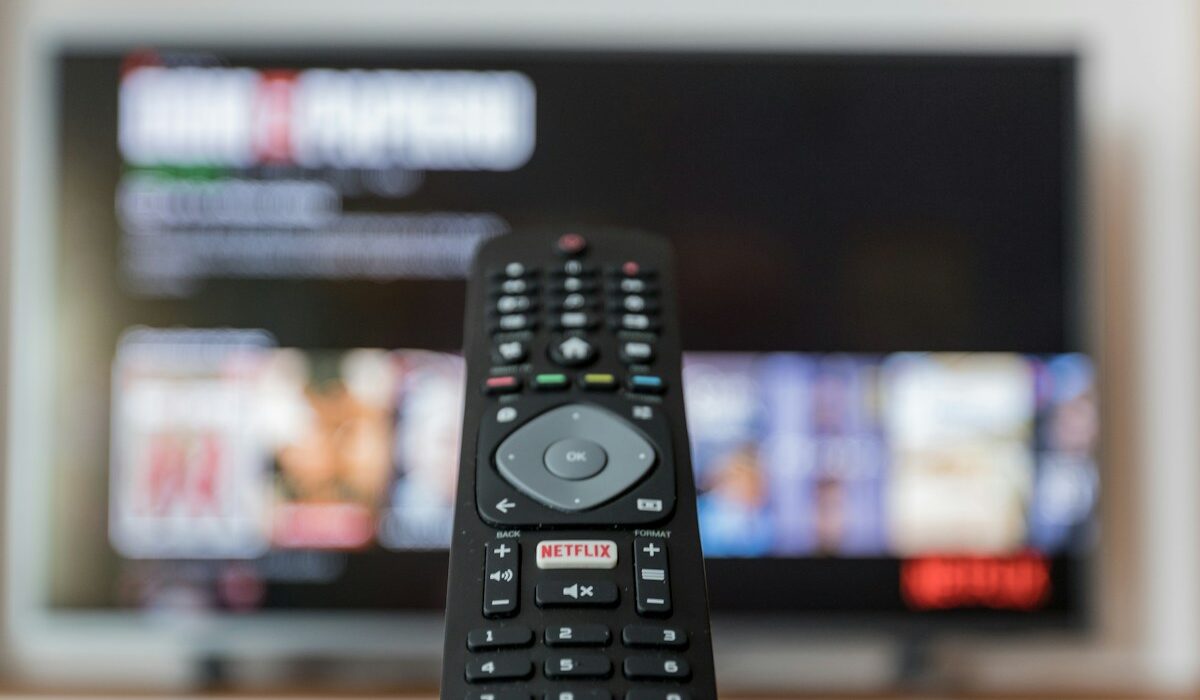 Netflix button on a television remote in front of a streaming screen