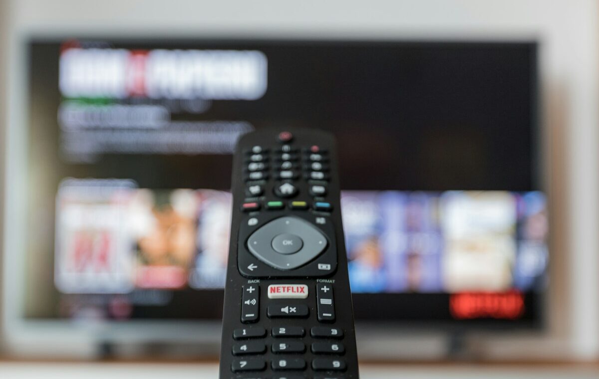 Netflix button on a television remote in front of a streaming screen