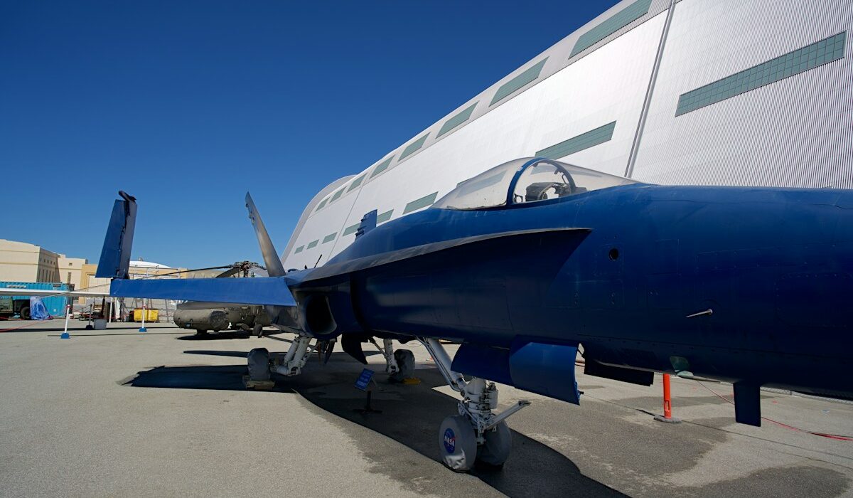 Blue military aircraft outside an aerospace hangar