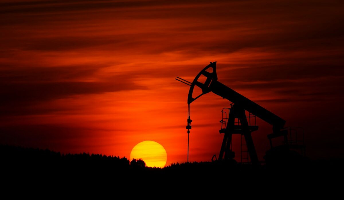 Oil pumpjack operating in an energy production field at sunset
