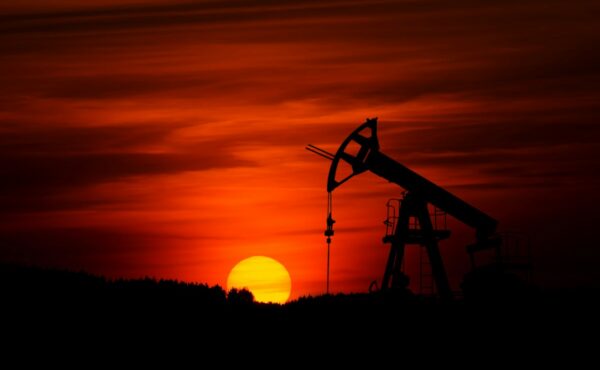 Oil pumpjack operating in an energy production field at sunset