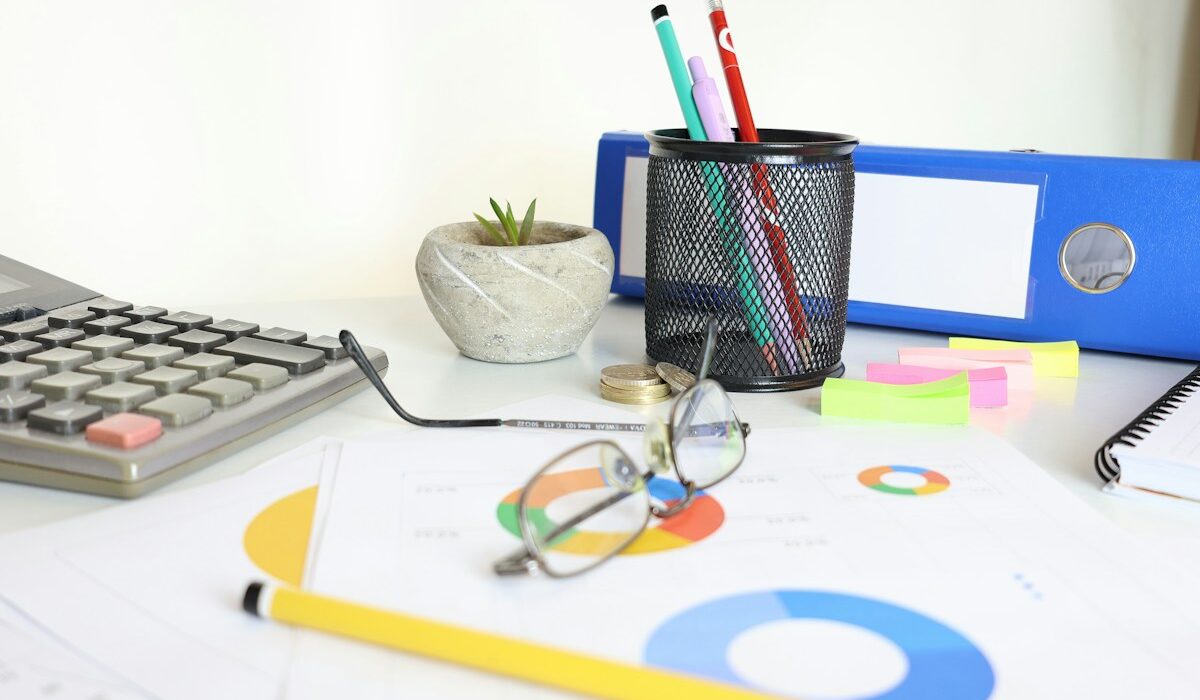 Calculator and financial reports illustrating price-to-earnings ratio analysis. Photo by Cht Gsml on Unsplash.