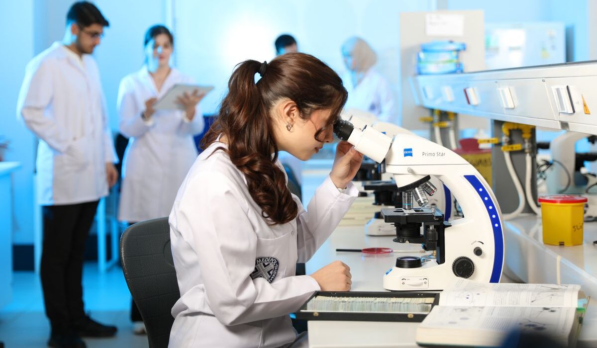 Biotechnology scientist using a microscope ahead of Regeneron third-quarter earnings