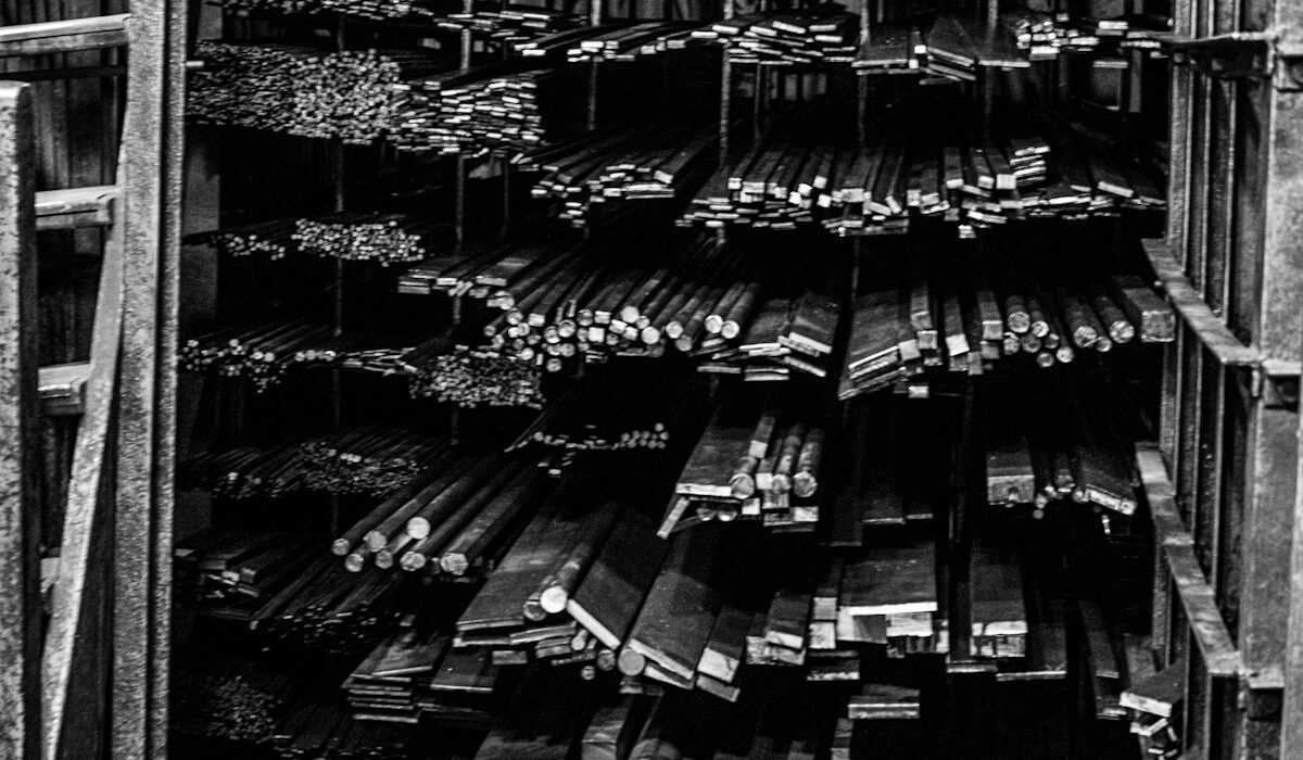 Stacked steel rods and metal stock in an industrial warehouse