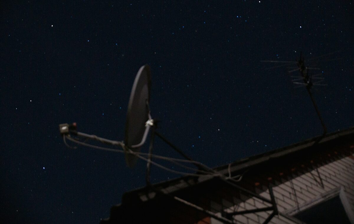 Starlink Mobile spectrum expansion represented by a rooftop satellite dish beneath a clear night sky.