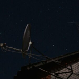 Starlink Mobile spectrum expansion represented by a rooftop satellite dish beneath a clear night sky.