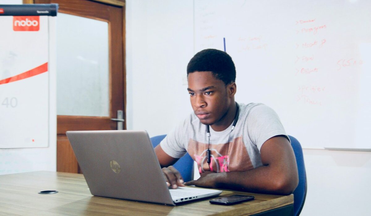 University student using a laptop while reviewing financial aid information