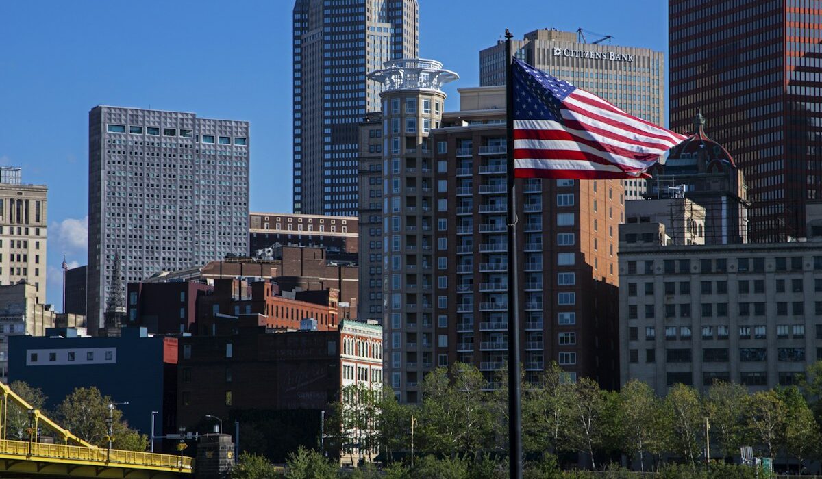 American flag before a city skyline representing the U.S. economy