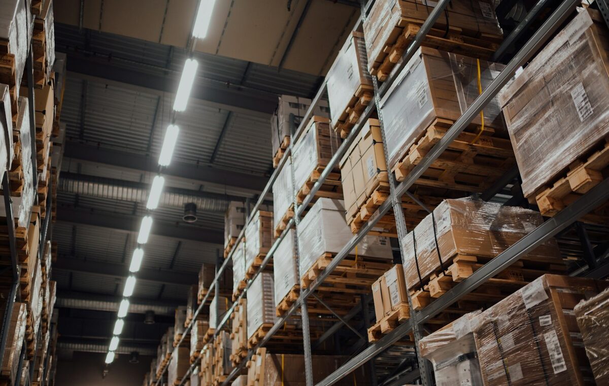 Warehouse shelves holding packaged inventory for turnover analysis. Photo by CHUTTERSNAP on Unsplash.