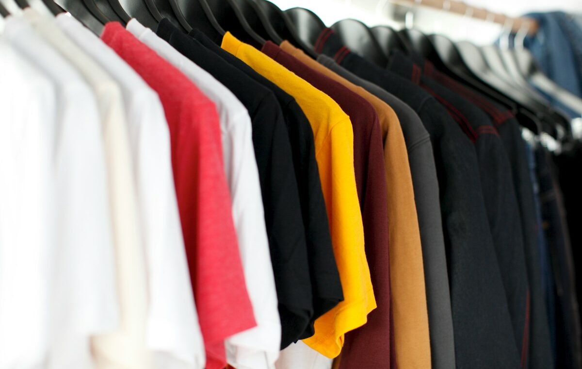 T-shirts on hangers representing wholesale apparel distribution. Photo by Parker Burchfield on Unsplash.